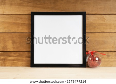 Photo frame with blank poster on wooden walls with red christmas ball