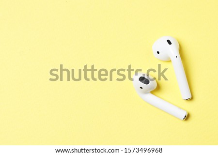 Wireless headphones on a yellow background with place for text. Royalty-Free Stock Photo #1573496968