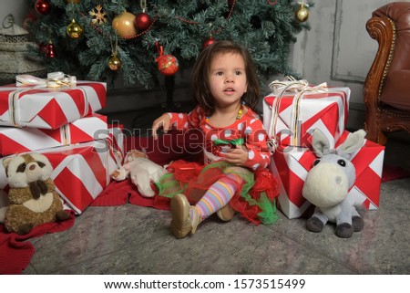 happy little girl in a red dress near the Christmas tree among gifts