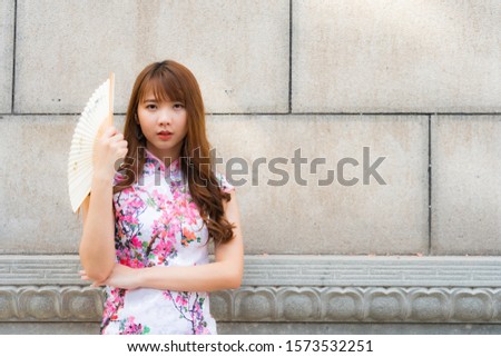 Portrait of Chinese girl wearing Chinese clothes holding paper folding fan in her hand