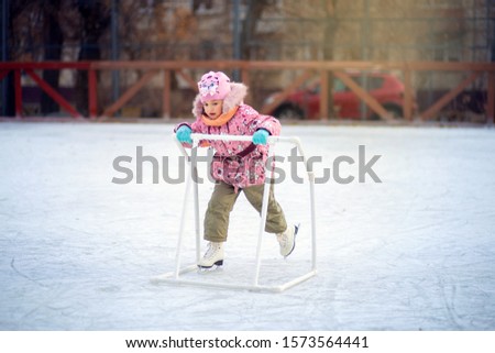 Happy child skates on an ice rink with a special support structure.
