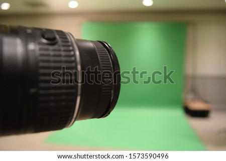 Professional photography studio showing behind the scenes lights, set up and green screen blurred in the background.