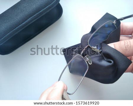 Black modern eyeglasses with case.Man wipes with a cloth the glass from contaminants.Cleaning glasses medical glasses.Glasses to restore vision.Glasses for the treatment of myopia and farsightedness.