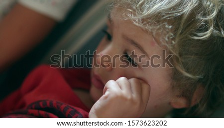 
Closeup of child boy face bored watching media content