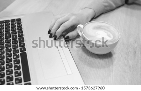 working moments on a laptop with a cup of coffee black and white background