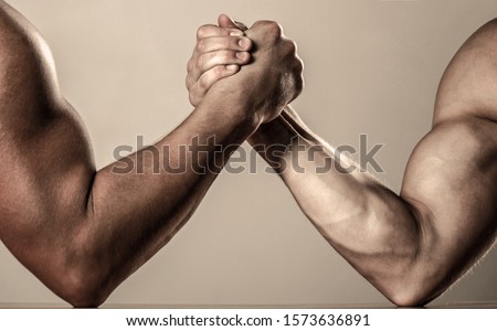 Hand wrestling, compete. Hands or arms of man. Muscular hand. Clasped arm wrestling. Two men arm wrestling. Rivalry, closeup of male arm wrestling. Muscular men measuring forces, arms.