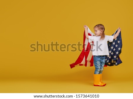 Patriotic holiday. Happy child, cute little girl with american flag on yellow studio background. USA celebrate July 4th, independence Day.