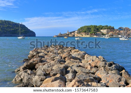 The photo was taken in an area called Porto Cristo on the island of Palma de Mallorca. The picture shows a picturesque sea bay on a sunny day. On the cape a lighthouse is visible.