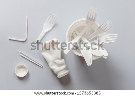 Used white plastic on a gray background. The concept of protecting the environment from plastic waste contamination. Flat lay Royalty-Free Stock Photo #1573653385