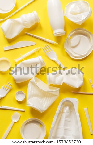 Used white plastic packaging for food on a yellow background. The concept of protecting the environment from plastic waste contamination. Flat lay Royalty-Free Stock Photo #1573653730