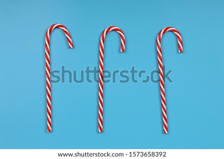 Creative christmas background. Striped candies on a blue background. Minimalistic scandy style. Empty space for text, top view, flat lay
