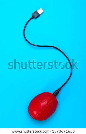 A USB cable is inserted into the brain on a blue background, brain control, a man and a computer, a biomachine.