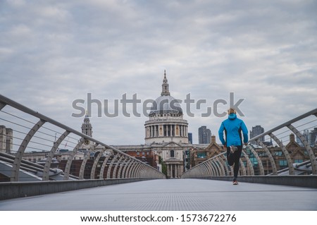 London marathon concept photo. Runner training on Millennium Footbridge, St Paul's Cathedral in background.