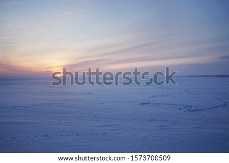 Snowy field and snow kiteboarders against the backdrop of a beautiful sunset.       