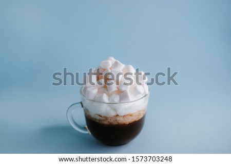 cup of coffee with whipped cream and marshmallows on a blue background