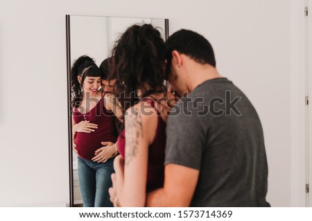 young couple at home hugging. Happy Pregnant woman. Reflection on mirror