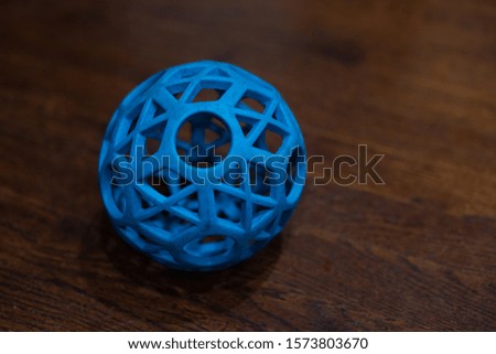A cool blue dog toy sitting inside on a wooden floor. 
