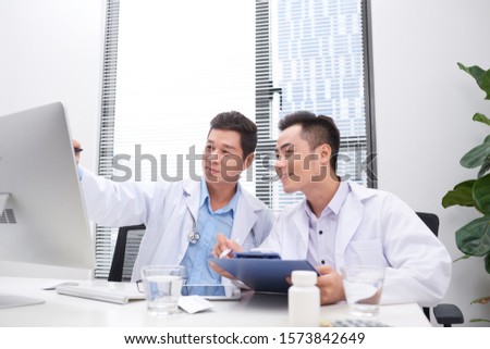 Two doctors holding and talking about patient on office