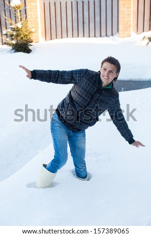 Young man in a winter boots fell into a deep white snow