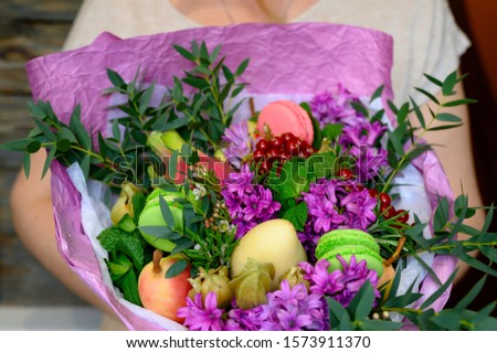 photo from a series of pictures about the process of forming a fruit and flower bouquet. tutorial, do it yourself. photo 40, a woman holds a finished bouquet on a wooden background