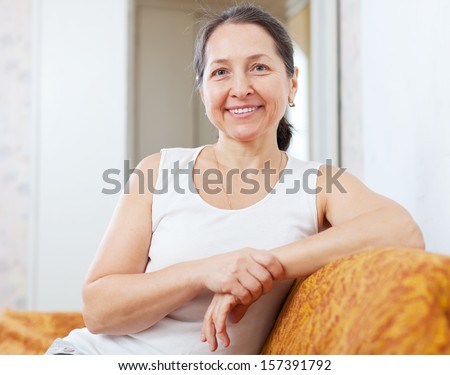 Smiling ordinary mature woman in home interior Royalty-Free Stock Photo #157391792