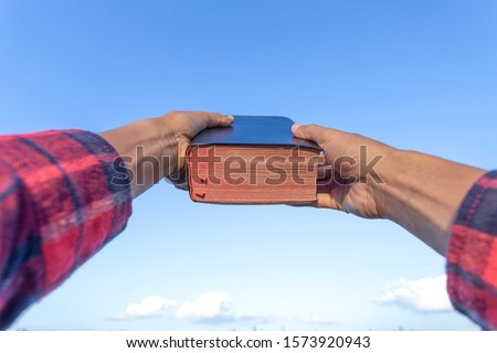Man hand is holding a bible up to the sky. Christian concept background.