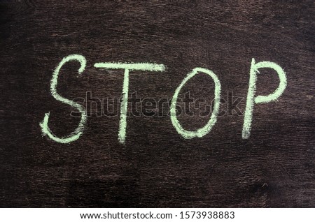 Colorful chalk drawing: the word STOP written in chalk on a black chalkboard.