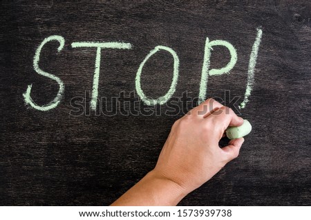 hand draws in chalk: the word "Stop". The inscription in chalk on a black chalkboard.