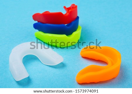 many colored boxing mouth guards lie on a blue background, sports concept Royalty-Free Stock Photo #1573974091