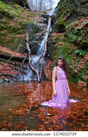Beautiful young hispanic woman in a pond by a waterfall