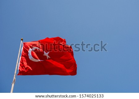 Turkish national flag with white star and moon on a pole in sky