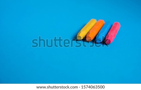 yellow orange blue red color crayons on blue background
