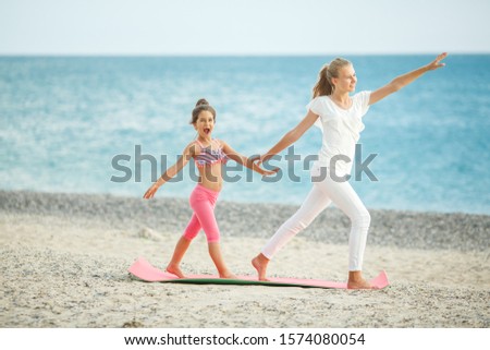 
Two sisters doing yoga by the sea