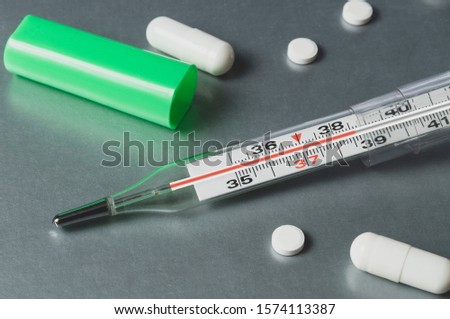 thermometer and tablets, thermometer shows elevated temperature, diagnosis and prevention of diseases