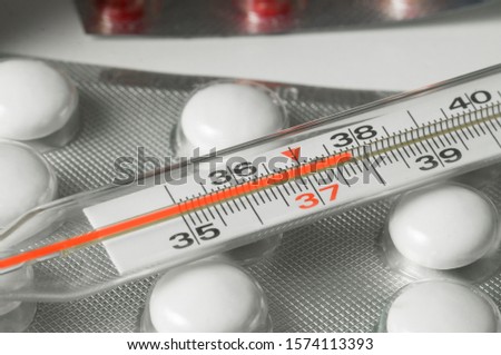a thermometer and pills, the thermometer shows a higher temperature, a symptom of the disease of influenza