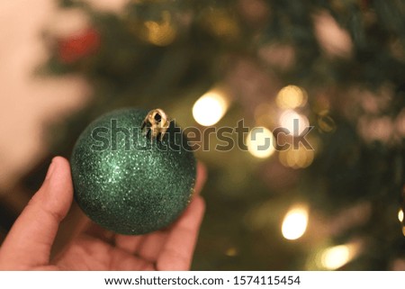 Close up pictures, woman hand decorating the Christmas tree with green balls
