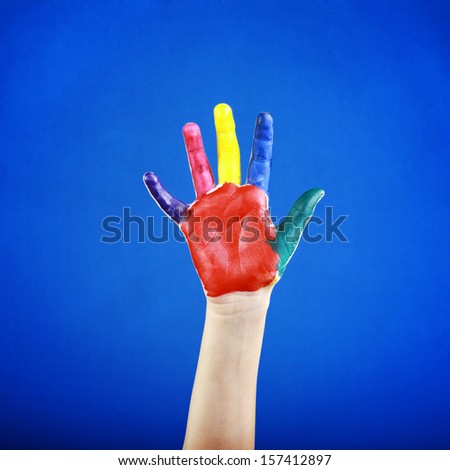 Child's hand painted with multicolored finger paints on blue background 