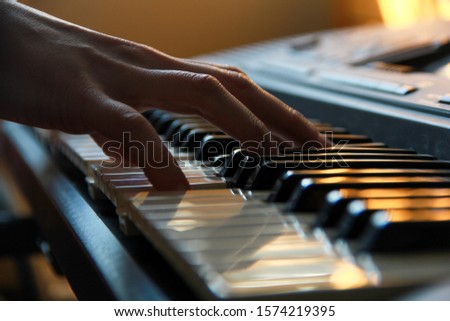 Details of a hand playing on keyboard under a smooth light