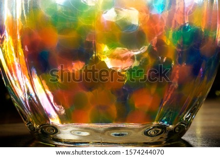 Colorful balls in a water-filled vessel of thick glass. The vessel stands on the floor and is illuminated by a backlight