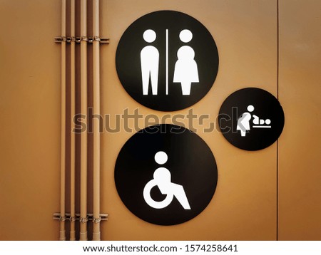 Set of White Toilet Symbols in Black Circled Plates on Brown Wall