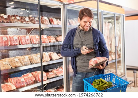 Man scans a meat product with smartphone app while shopping in supermarket