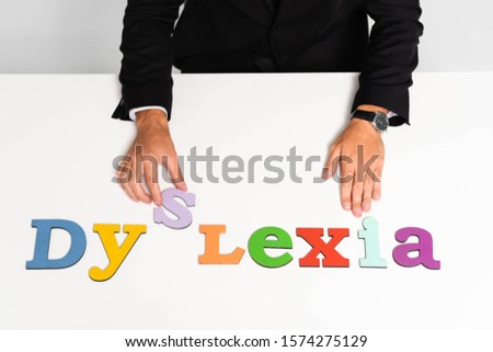 cropped view of businessman in suit sitting near dyslexia lettering 