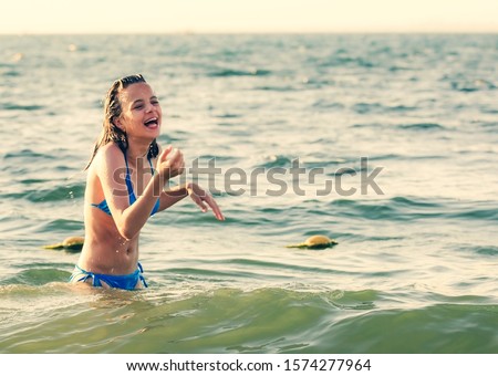 Portrait of a dark-haired wet laughing woman teen in a swimsuit on a summer evening in the light of the setting sun. Copy space