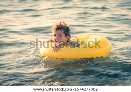 Happy Child on an yellow inflatable circle floating on the black sea