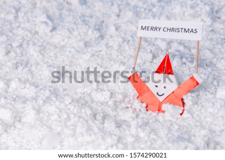 Little origami paper Santa holding the inscription "Merry world". Fake snow. Copy space.
