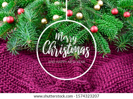 Merry Christmas and Happy New Year Sign on knitted background. Christmas purple background with ornate spruce branch. Christmas tree branch on a purple background. Beautiful knitted warm background