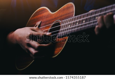 Hands playing acoustic guitar ukulele Royalty-Free Stock Photo #1574355187