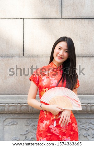 Portrait of Chinese girl wearing red clothes holding paper folding fan in her hand