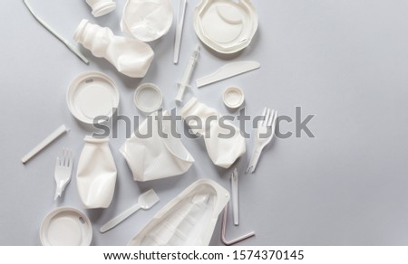 Used white plastic packaging for food on a gray background. The concept of protecting the environment from plastic waste contamination. Flat lay Royalty-Free Stock Photo #1574370145