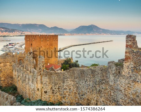 Alanya, Turkey. Beautiful view of the walls of the ancient fortress Alanya castle, the Red Tower Kızıl Kule and The Mediterranean Sea. Vacation postcard background